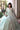Seated view of the Laila mint green bridal dress showing the motif-scattered skirt and the embellished dupatta border
