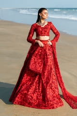 Ruby red Pakistani bridal lehenga choli, full front view on the beach with embroidered net lehenga and embellished dupatta