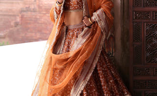 Gurleen rust brown bridal lehenga choli with organza dupatta under haveli arches, by Waqas Shah