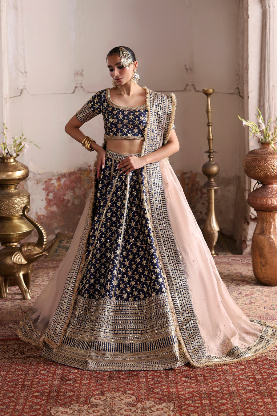 Geet navy blue raw silk lehenga choli, front view with champagne tissue dupatta under a white carved arch