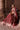 Bride seated in Bazaar burgundy Pakistani bridal lehenga, velvet skirt fanned out with embellished border