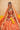Aabroo rust orange Pakistani mehndi lehenga worn with a marigold garland, front view