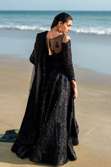 Back view of the Black Musk black formal lehenga with sheer net back, tassel tie and net dupatta over the shoulder