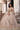 Dilnashin champagne gold bridal lehenga seated, with the flared chevron skirt spread out and striped tissue net dupatta