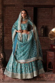 Manzil luxury teal and turquoise Pakistani bridal lehenga by Waqas Shah Official featuring a richly embroidered velvet ensemble with intricate jaal work.
