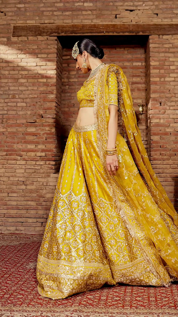 Video of Resham yellow Pakistani mehndi lehenga choli in motion, showing the tilla and mirror work, flare and organza dupatta – Waqas Shah