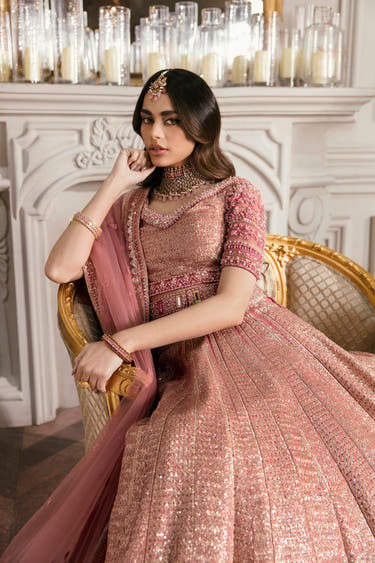 Model seated in the Primrose blush pink lehenga choli with sheer net dupatta and hand-embellished sleeves