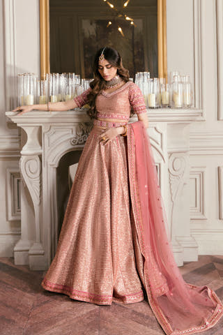 Primrose tea pink Pakistani & Indian bridal lehenga choli with rose-gold sequins, full front view by a marble fireplace