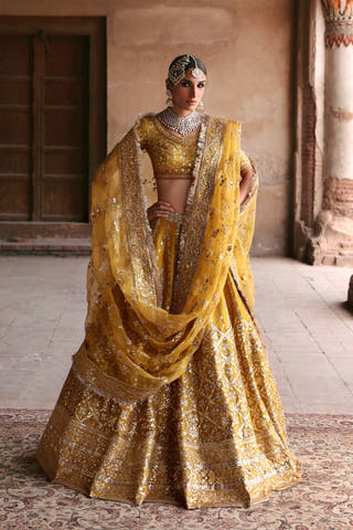 Resham yellow raw silk mehndi lehenga with organza dupatta draped across both arms