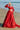 Full-length Ruby red barat lehenga with the embellished dupatta trailing on the sand