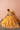 Zari mustard yellow mehndi lehenga seated, adjusting the organza dupatta over the flared skirt