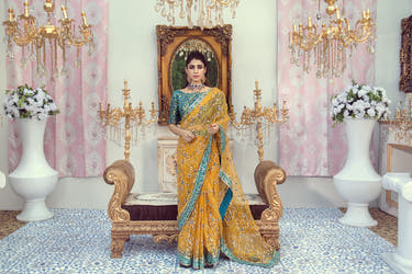 Yellow Gold Organza saree with Zinc Blue border and multicolour floral embellishment by Waqas Shah Official